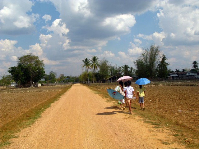 В Лаосе все ходят, и даже ездят на мотоциклах с зонтиками