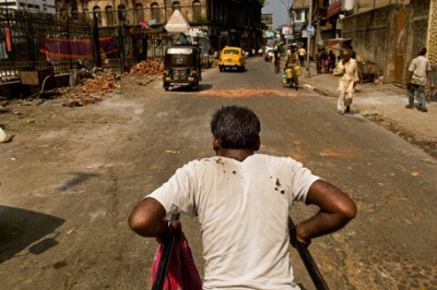 Рикша с трудом тащит повозку по ухабам одной из улиц Калькутты. Для него это единственный способ заработать на жизнь.
